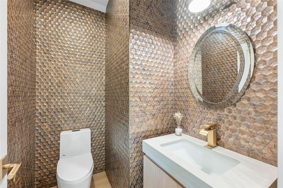 An eye-catching, textured wall with geometric tiles creates a unique powder room ambiance. An eye-catching, textured wall with geometric tiles creates a unique powder room ambiance.