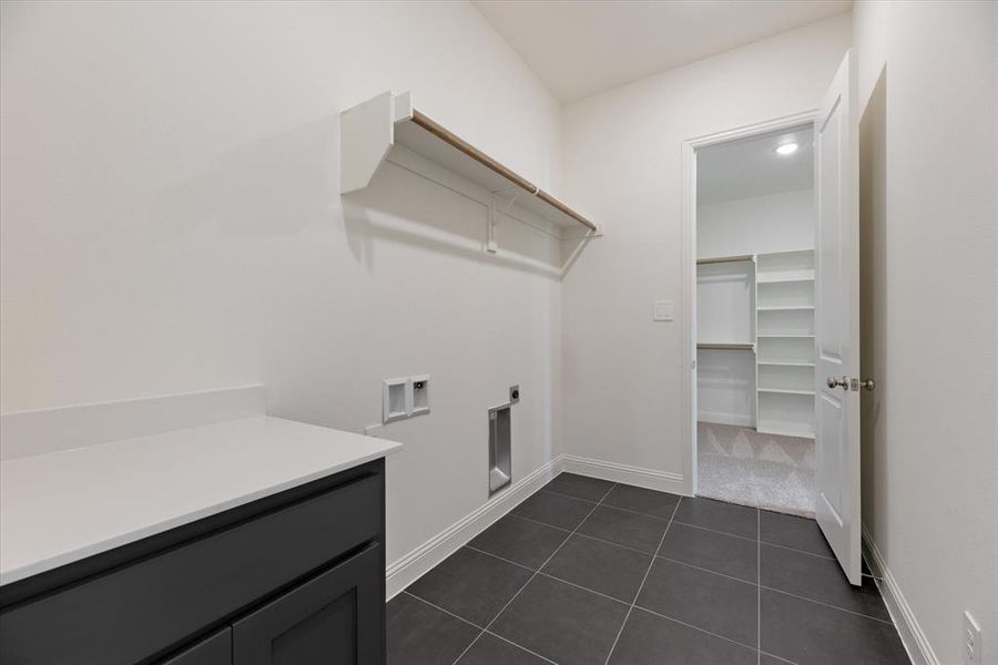 Laundry room featuring dark tile patterned flooring, hookup for a washing machine, hookup for an electric dryer, and cabinets