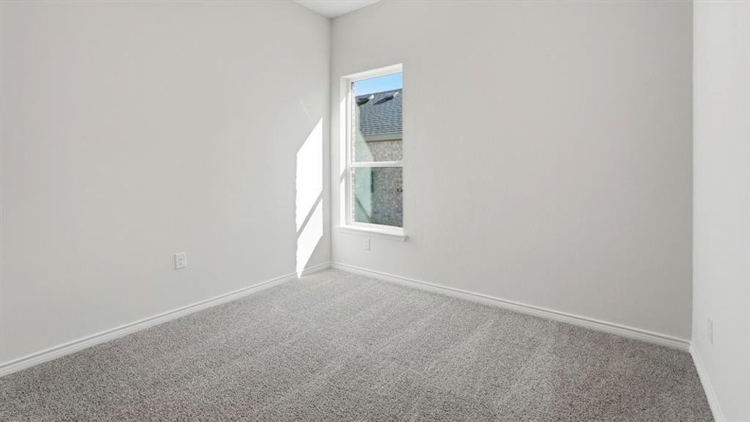 This room features light gray carpeting, white walls, and a window with a white frame This room features light gray carpeting, white walls, and a window with a white frame
