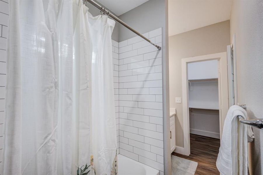 Bathroom featuring vanity, shower / bath combo with shower curtain, and wood-type flooring