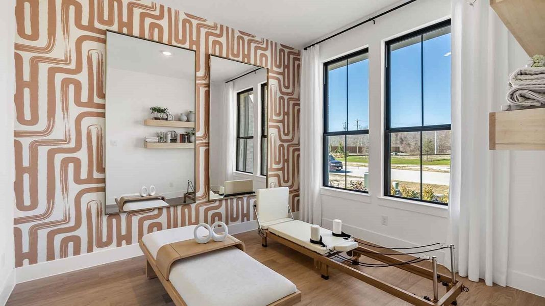 A bedroom shown as a home gym, with a bright window allowing natural light to enter.