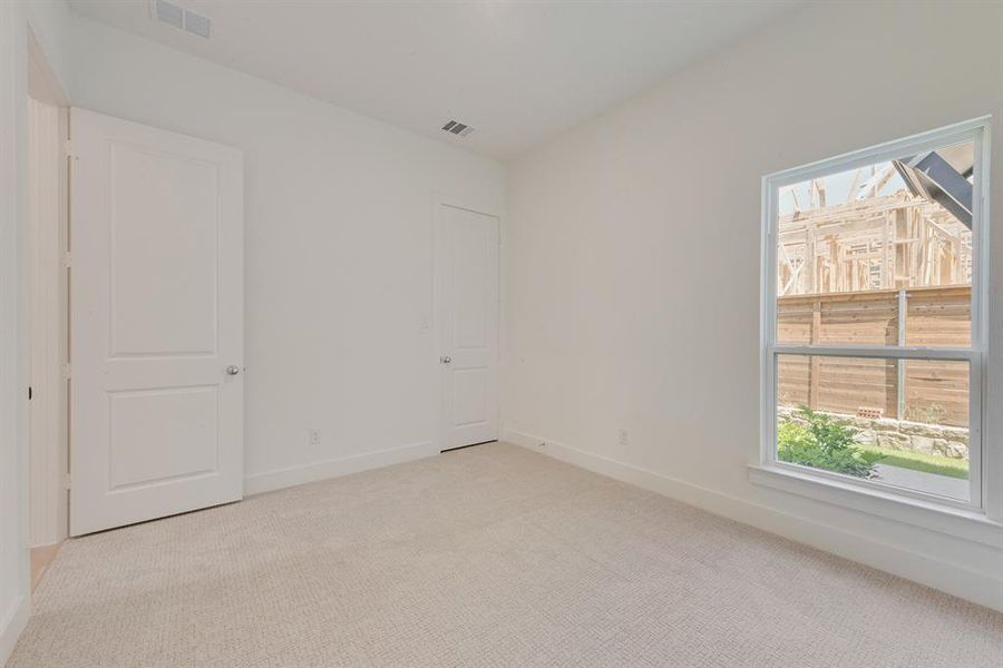 Spare room featuring plenty of natural light and light colored carpet Spare room featuring plenty of natural light and light colored carpet