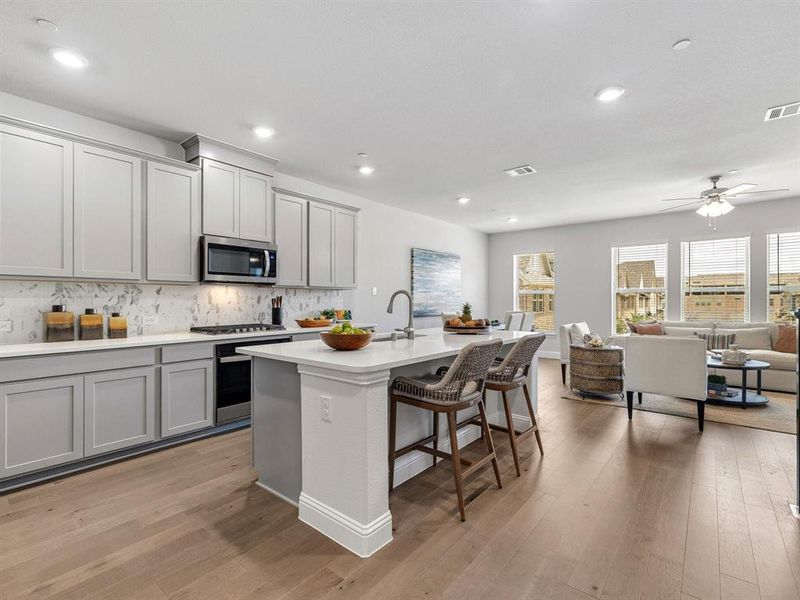 The chef's kitchen centers around an oversized quartz island featuring breakfast bar seating and premium under mount extra large sink.