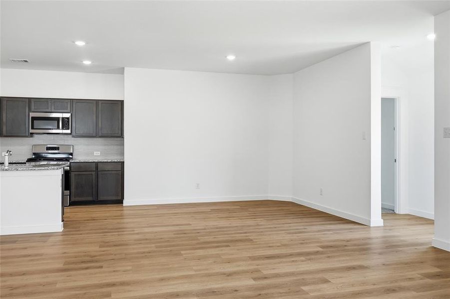 Kitchen featuring stainless steel appliances, light stone counters, light wood-style floors, recessed lighting, and open floor plan