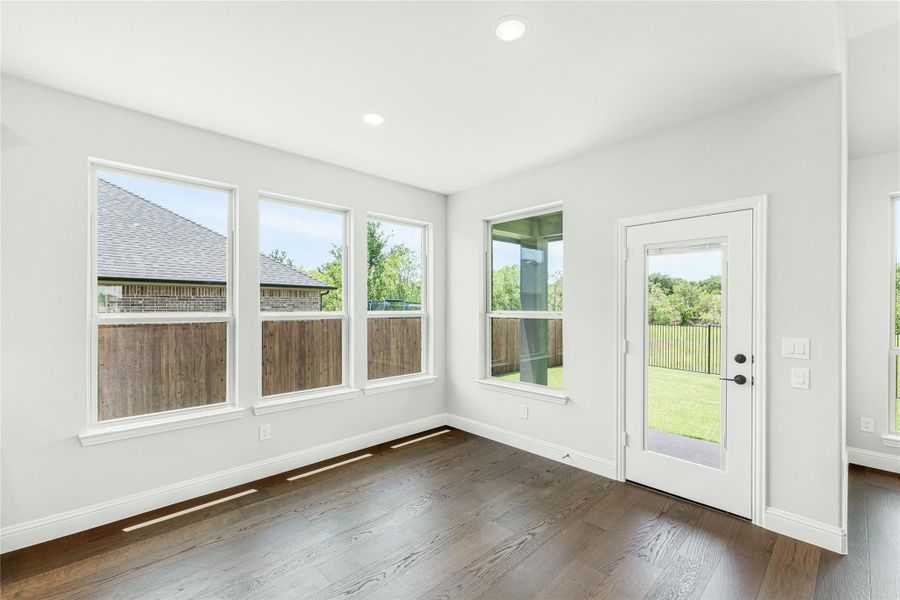 Bright empty room with dark hardwood floors, multiple windows, and a glass back door leading to a yard. Bright empty room with dark hardwood floors, multiple windows, and a glass back door leading to a yard.