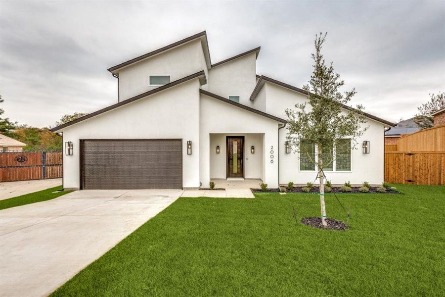 View of front of property featuring a garage and a front lawn