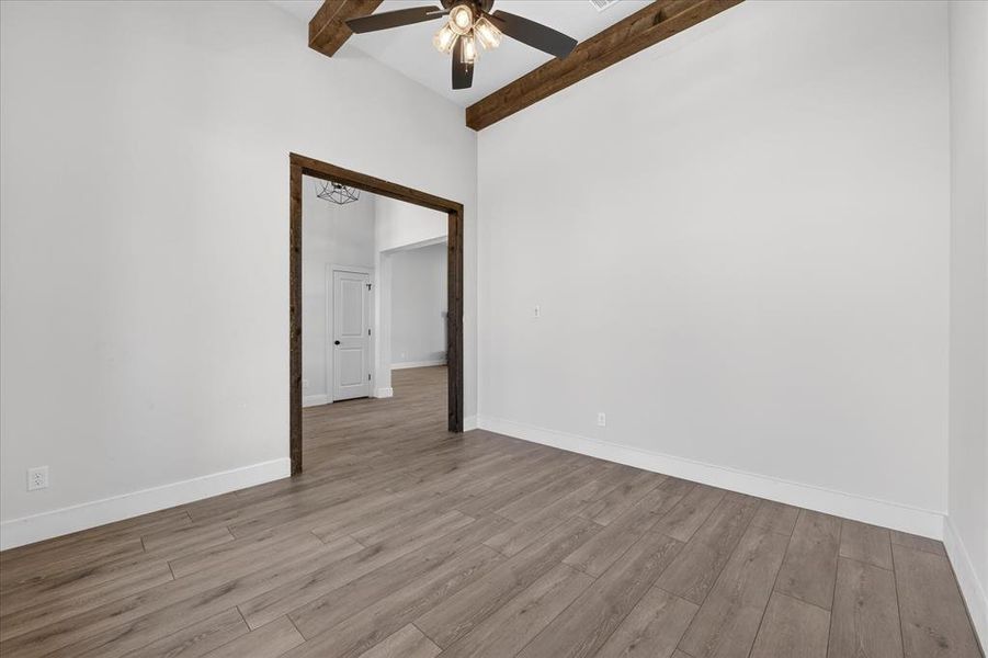 Empty room with a ceiling fan, wood finished floors, and vaulted ceiling