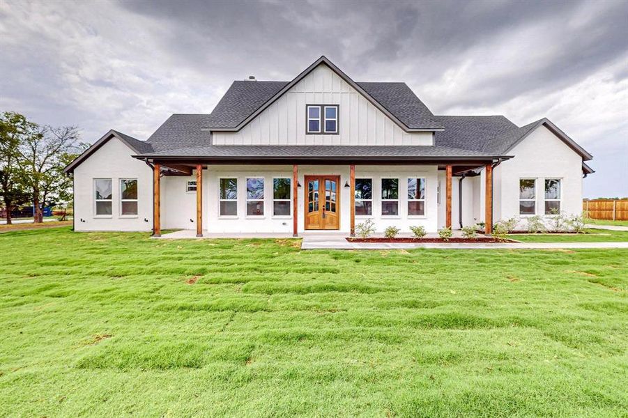 Modern inspired farmhouse with a front yard and covered porch