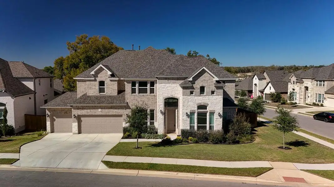 French country home featuring a front lawn, concrete driveway, a residential view, a garage, and stone siding