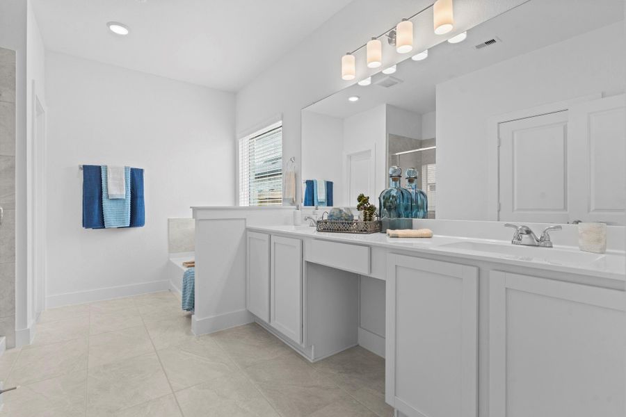 Step into your luxurious primary bath retreat, complete with dual vanities topped with elegant cultured marble counters, chic modern lighting, and sleek cabinetry—designed to pamper and impress. **Image Representative of Plan Only and May Vary as Built**.