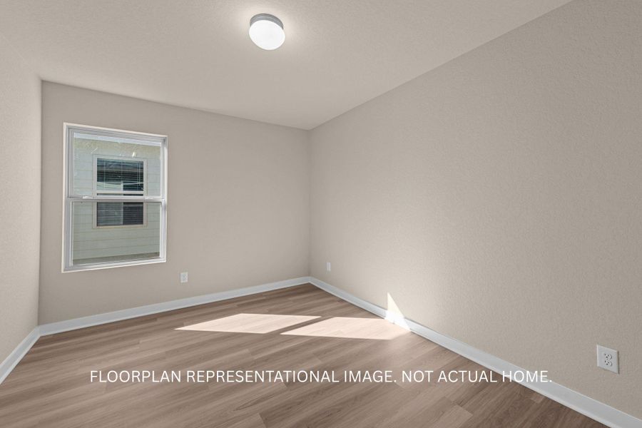 A well-lit bedroom features durable laminate flooring and a bright window.