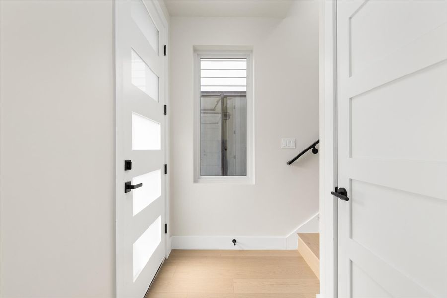 Clean lines and light wood flooring define this welcoming modern entryway and staircase.