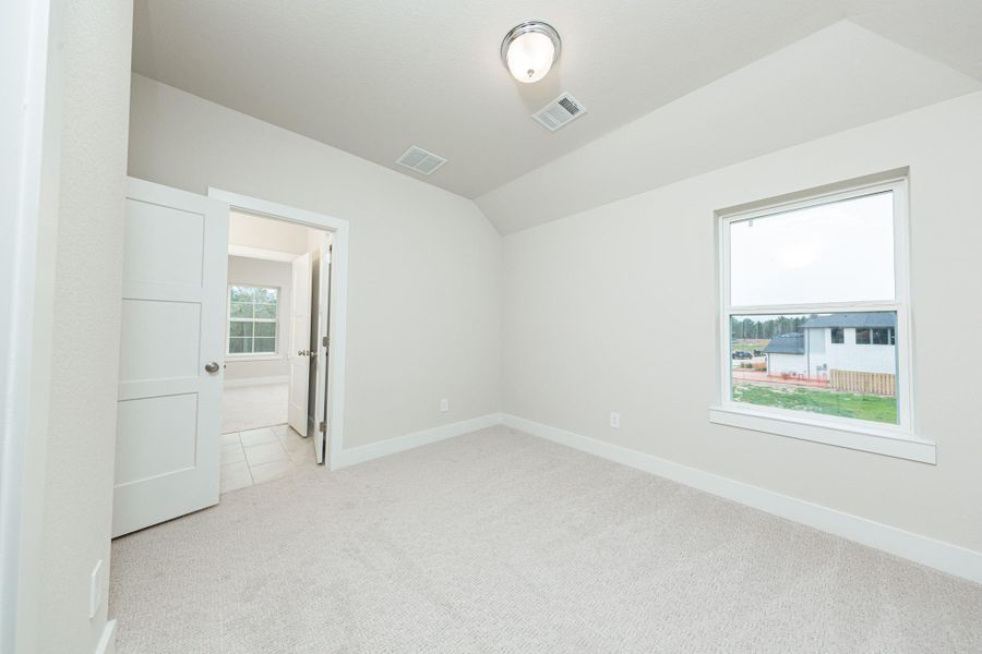 This inviting secondary bedroom combines comfort and modern elegance, featuring plush carpeting, a neutral color palette, and abundant natural light streaming through a large window. Discover the efficiency and convenience of accessing the secondary bathroom with another secondary bedroom--a highly functional solution for busy families.