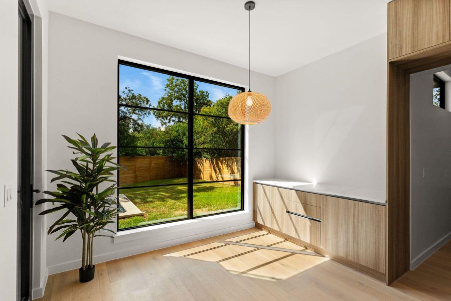 Natural light streams across rich wood flooring through a large window overlooking the yard.