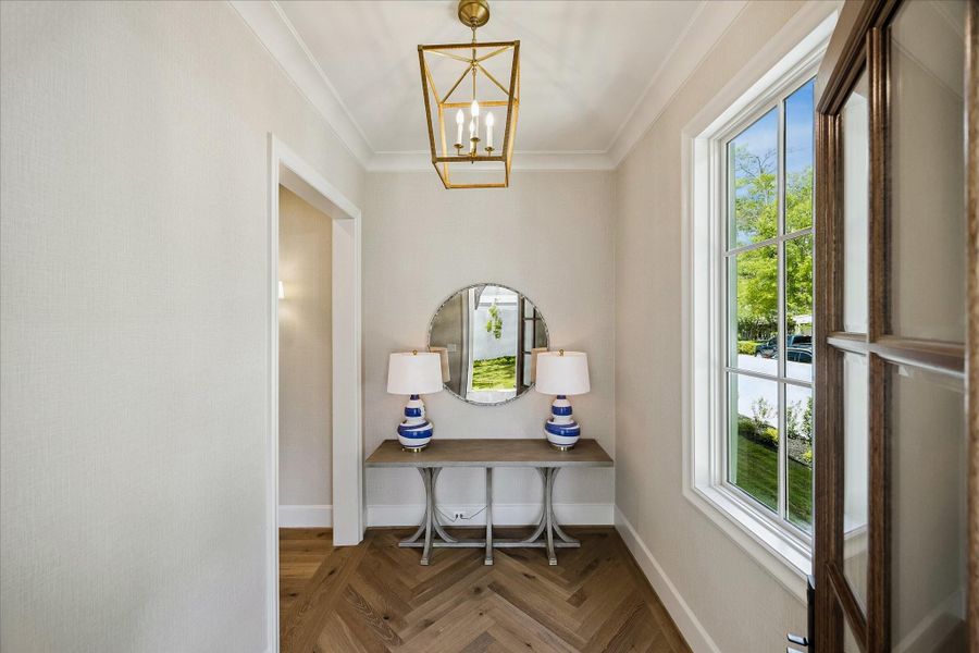 Elegant front entry featuring herringbone hardwood floors, designer lighting and refined trim details. Large divided light window fills the space with natural light and creates a beautiful introduction to the home.