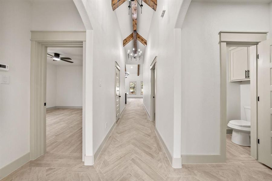 Corridor with a chandelier, beamed ceiling, a towering ceiling, and arched walkways