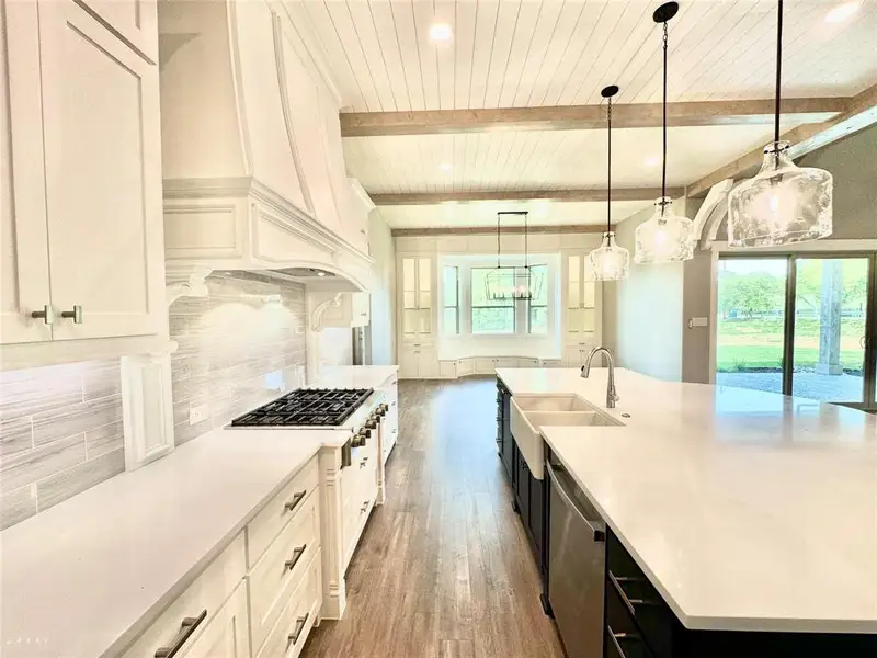 Kitchen with a sink, dishwasher, wood finished floors, plenty of natural light, and wooden ceiling with exposed beams