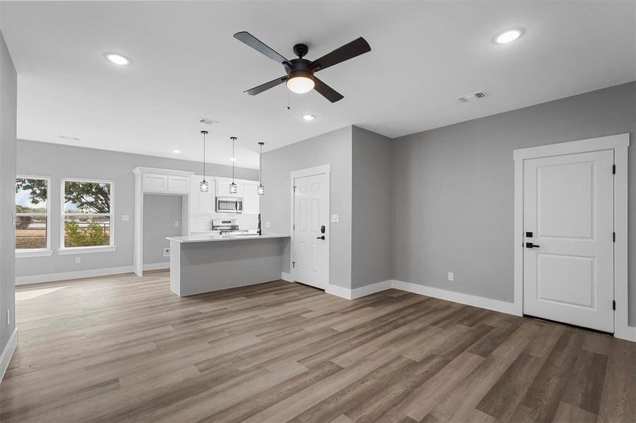 Unfurnished living room with light wood-type flooring and ceiling fan