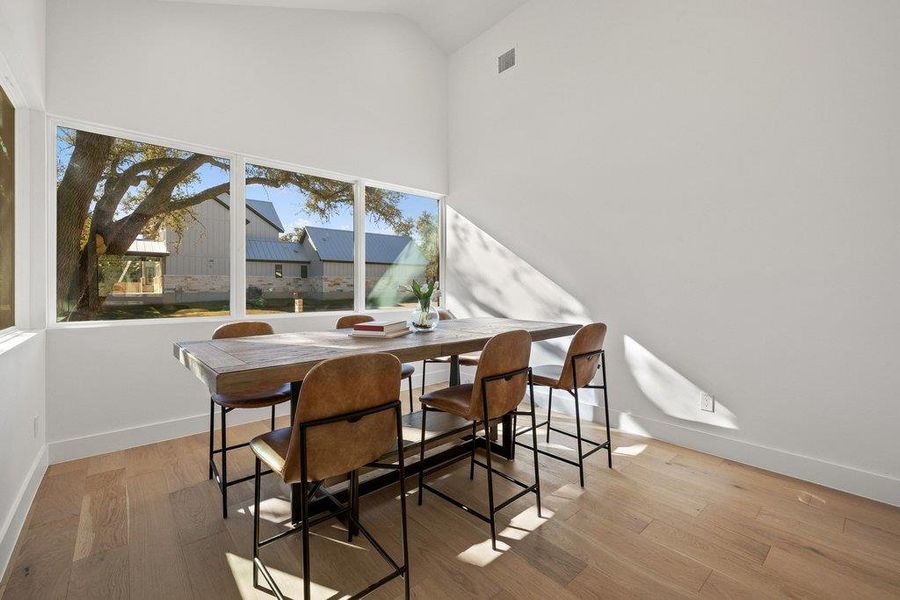 Dining area with light wood finished floors and high vaulted ceiling