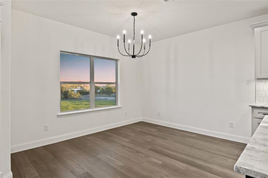 Unfurnished dining area featuring dark wood finished floors and a chandelier
