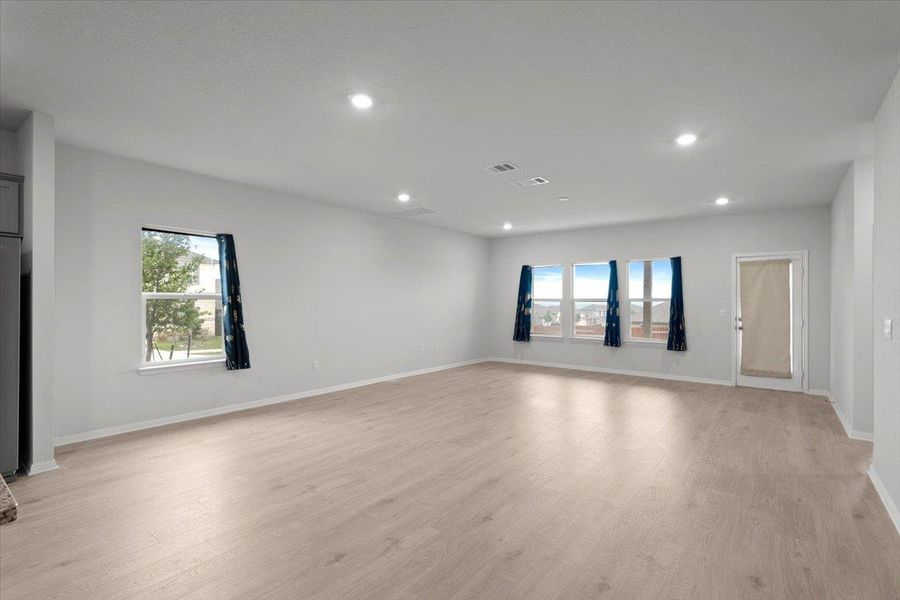 Spacious open-concept room featuring light wood-finish flooring and recessed lighting