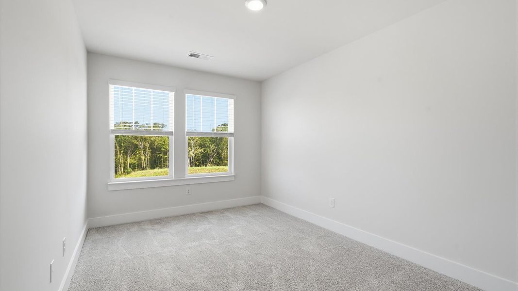 Bright and serene bedroom with comfortable carpeted flooring and large windows for vibrant light