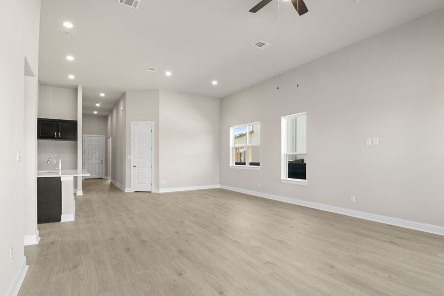 Image of a one story home living room with light brown flooring and light grey walls with a window and ceiling fans