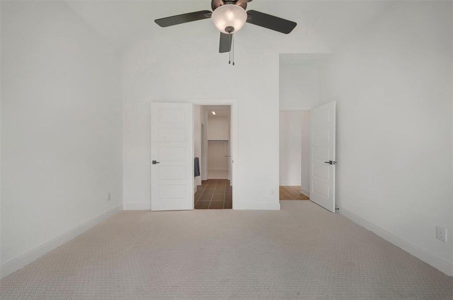 Carpeted room with a vaulted ceiling and a ceiling fan with integrated lighting