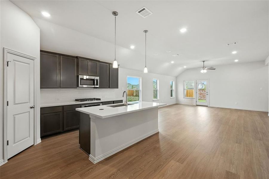 Kitchen with pendant lighting, vaulted ceiling, decorative backsplash, recessed lighting, and a kitchen island with sink Kitchen with pendant lighting, vaulted ceiling, decorative backsplash, recessed lighting, and a kitchen island with sink