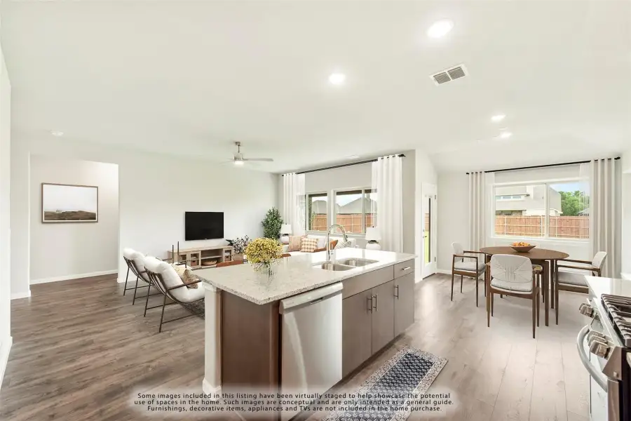 Open-concept kitchen with island, granite countertops, and wood floors flowing into dining and living areas with large windows