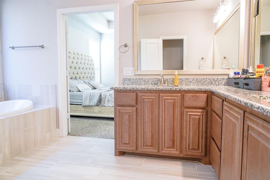 Bathroom with vanity, ensuite bath, tiled bath, and light tile patterned floors