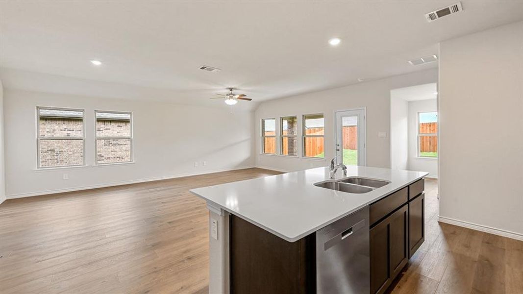 Open-concept living area featuring an island kitchen with a double basin sink and stainless steel dishwasher Open-concept living area featuring an island kitchen with a double basin sink and stainless steel dishwasher