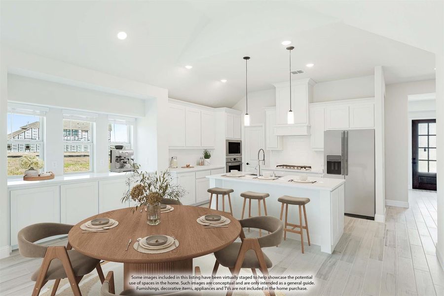 Open-concept kitchen and dining area with white cabinets, center island, pendant lights, and round wood dining table.