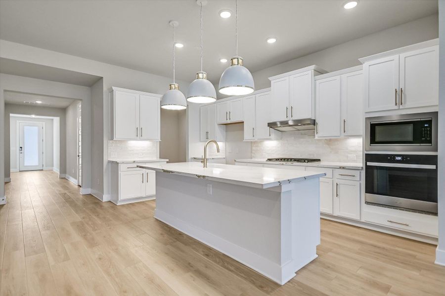 White shaker cabinets, stone countertops, and light wood flooring define this modern culinary space. White shaker cabinets, stone countertops, and light wood flooring define this modern culinary space.