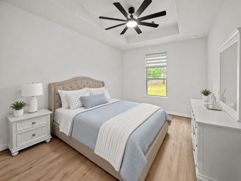 3rd bedroom with tray ceiling, modern ceiling fan, vinyl plank flooring, and backyard views.