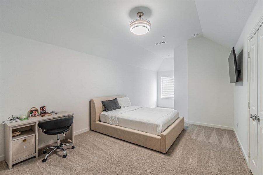Bedroom with light carpet, lofted ceiling, and a desk