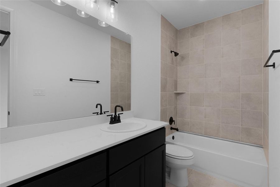 Bathroom featuring washtub / shower combination, vanity, and light tile patterned flooring