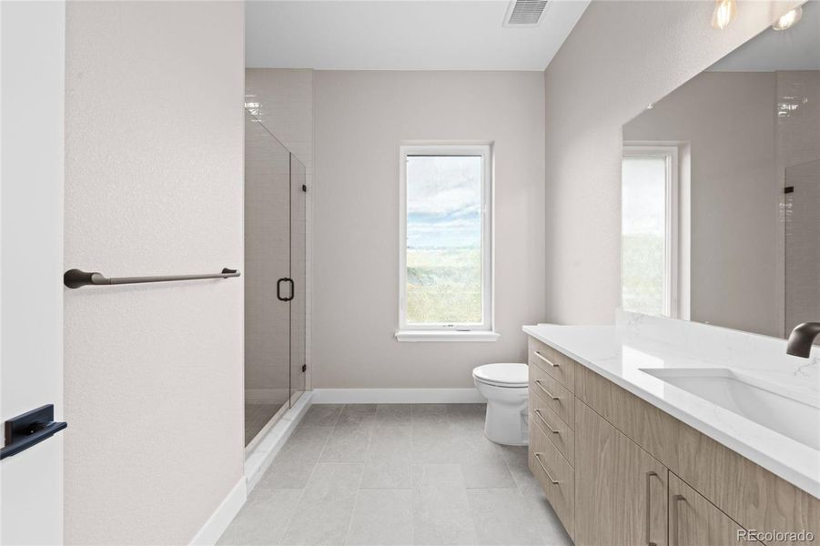 Main level en suite guest bathroom with quartz countertop and glass-faced shower.