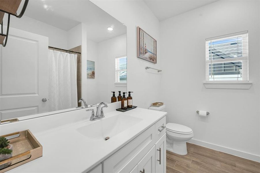 Bathroom featuring a shower with curtain, wood-type flooring, toilet, and vanity