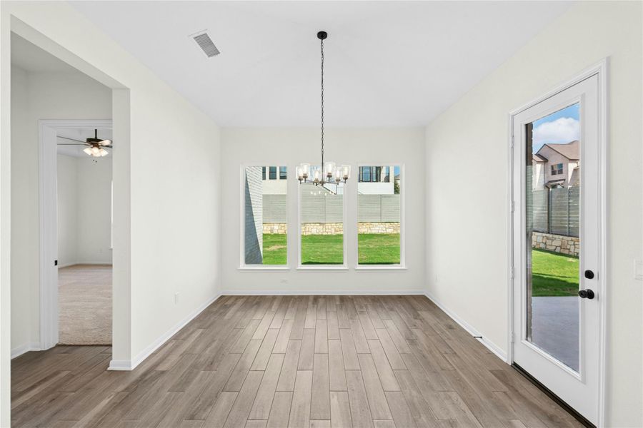 Unfurnished dining area with plenty of natural light, a chandelier, light wood finished floors, and ceiling fan Unfurnished dining area with plenty of natural light, a chandelier, light wood finished floors, and ceiling fan