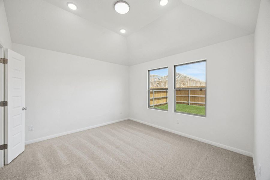 Carpeted empty room with vaulted ceiling and recessed lighting