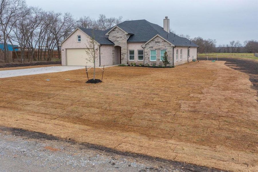 French country inspired facade with driveway, stone siding, and a chimney