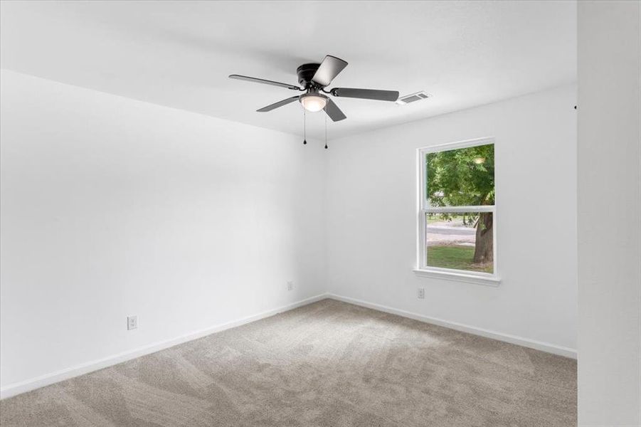 First bedroom with ceiling fan and carpet