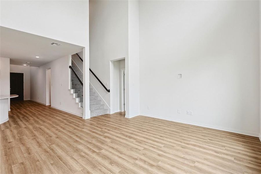 Unfurnished living room featuring light hardwood / wood-style floors and a towering ceiling