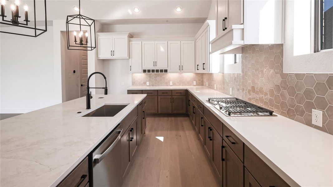Kitchen featuring tasteful backsplash, light wood-type flooring, white cabinetry, stainless steel appliances, and pendant lighting Kitchen featuring tasteful backsplash, light wood-type flooring, white cabinetry, stainless steel appliances, and pendant lighting