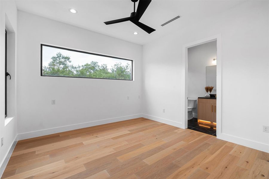 This room features light hardwood flooring, white walls, and a window providing views of greenery