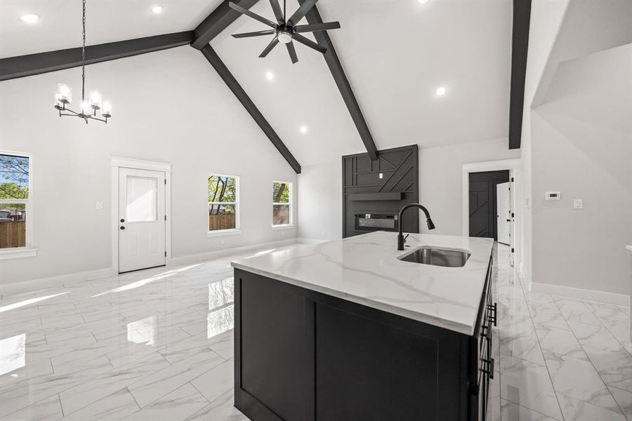 Kitchen with stainless steel appliances, exhaust hood, light stone countertops, light marble finish floors, and dark cabinets