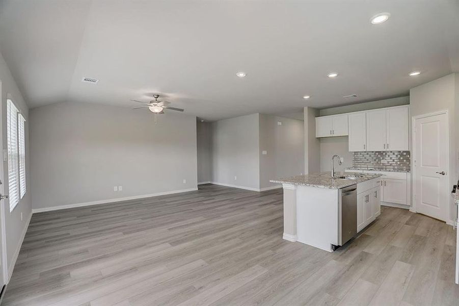 Kitchen featuring white cabinets, an island with sink, light hardwood / wood-style floors, and stainless steel dishwasher