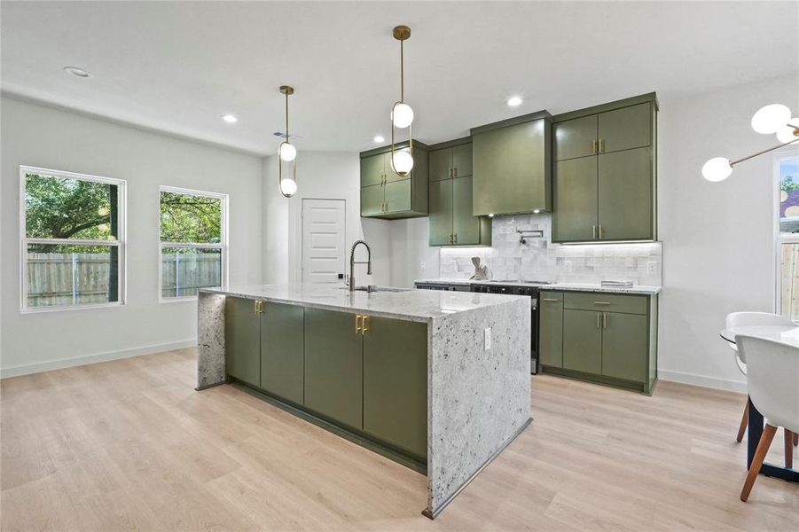 Kitchen with green cabinets, light stone counters, healthy amount of natural light, decorative backsplash, and recessed lighting