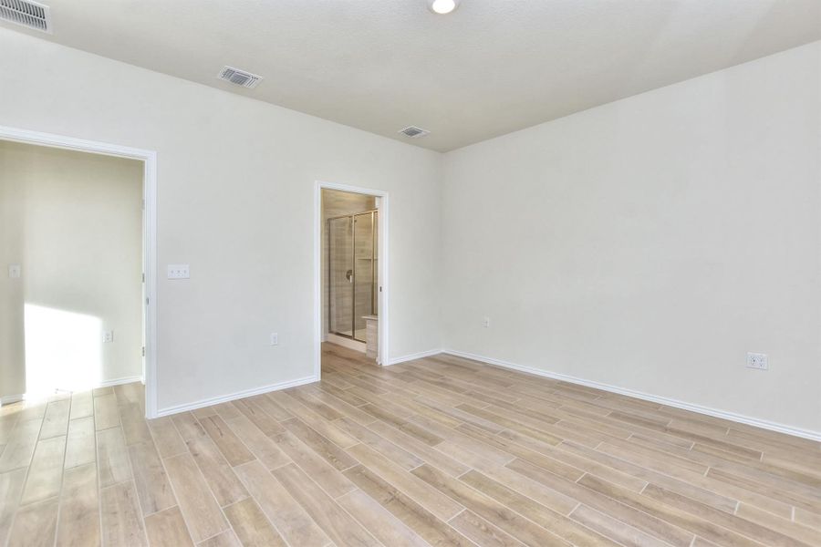 Primary room with light wood-style floors, visible vents, and baseboards